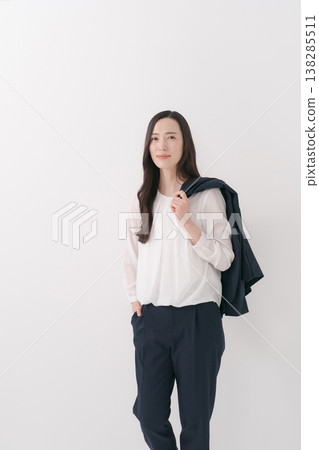 一位身穿西裝的女士，肩上披著一件外套。 138285511