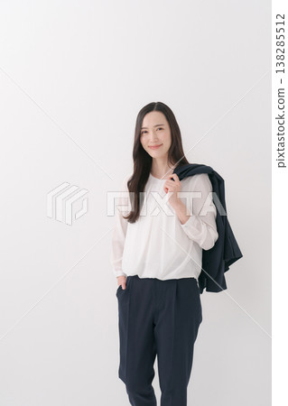 A woman in a suit with a jacket draped over her shoulders. 138285512