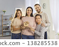 Happy family holding tiny house model on hands moving new flat, advertising real estate agent 138285538
