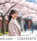 A spring portrait of a woman smiling gently as she looks back amidst a row of cherry trees in full bloom. 138285674