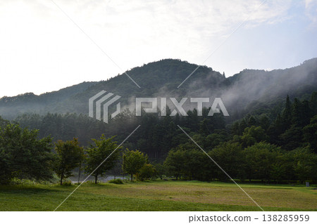 山巒和森林籠罩在薄霧之中;一個自然的清晨;霧氣瀰漫的山巒景色。 山巒和森林籠罩在薄霧之中;一個自然的清晨;霧氣瀰漫的山巒景色。 138285959