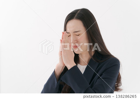 一位身穿西裝的女子雙手合十,做出祈禱的姿勢。 一位身穿西裝的女子雙手合十,做出祈禱的姿勢。 138286265