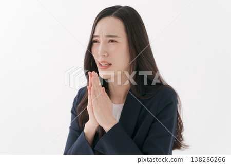 一位身穿西裝的女子雙手合十,做出祈禱的姿勢。 一位身穿西裝的女子雙手合十,做出祈禱的姿勢。 138286266