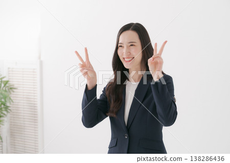 A woman in a suit making a peace sign 138286436