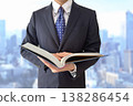 A man in a suit opening a book against a city backdrop. 138286454