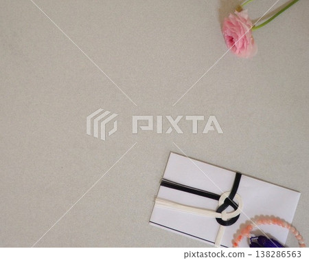 Prayer beads, a condolence envelope, and pink flowers 138286563