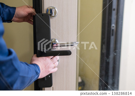 The technician installs a smart electronic lock on the front door. 138286814