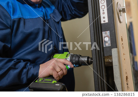 The technician installs a smart electronic lock on the front door. 138286815