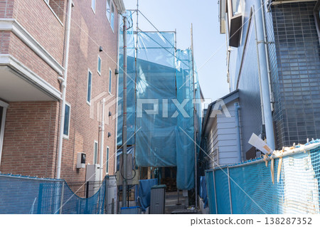 一棟正在興建中的木製獨立房屋，位於一塊旗形地塊上，入口狹窄。 138287352