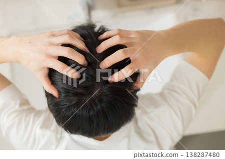 一位年輕男子在浴室裡梳頭。 一位年輕男子在浴室裡梳頭。 138287480