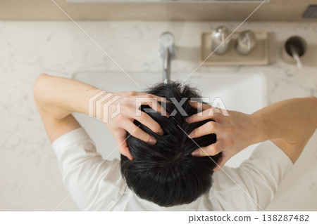 A young man doing hair care in the bathroom. A young man doing hair care in the bathroom. 138287482
