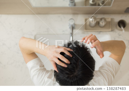 一位年輕男子在浴室裡梳頭。 一位年輕男子在浴室裡梳頭。 138287483