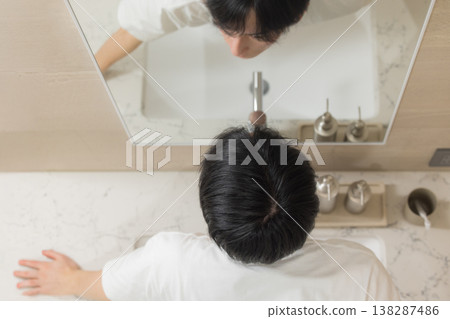 A young man doing hair care in the bathroom. A young man doing hair care in the bathroom. 138287486