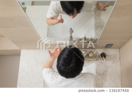 A young man doing hair care in the bathroom. 138287488