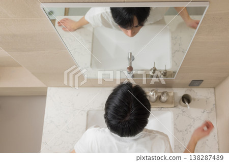 A young man doing hair care in the bathroom. 138287489