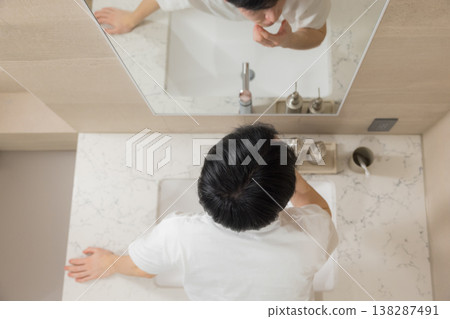 一位年輕男子在浴室裡梳頭。 一位年輕男子在浴室裡梳頭。 138287491