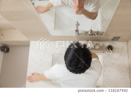 A young man doing hair care in the bathroom. A young man doing hair care in the bathroom. 138287492