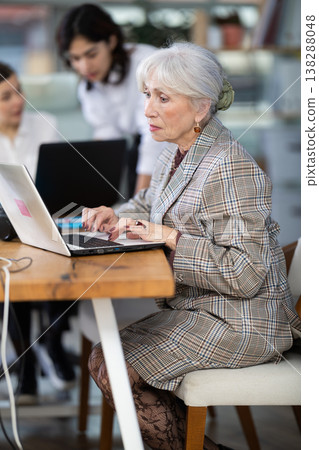 Mature woman working on laptop during busy corporate session 138288048