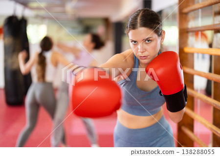 Young woman practicing punch with boxing gloves Young woman practicing punch with boxing gloves 138288055