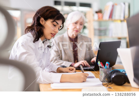 Focused young girl engaged in paperwork at her workplace Focused young girl engaged in paperwork at her workplace 138288056