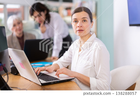 Focused middle-aged woman working on laptop during busy corporate session Focused middle-aged woman working on laptop during busy corporate session 138288057