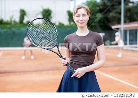 Woman in sportswear against backdrop of outdoor tennis court. Woman in sportswear against backdrop of outdoor tennis court. 138288148