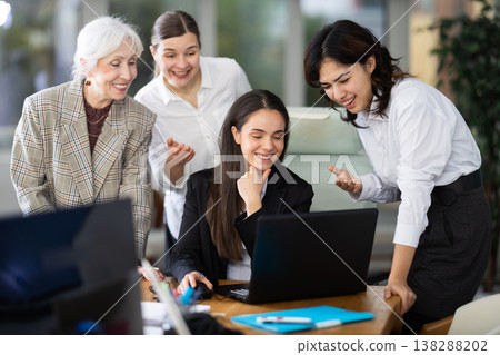 Group of women laughing together around laptop in office Group of women laughing together around laptop in office 138288202