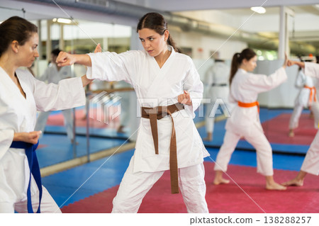 Womens practicing new karate moves in pairs in class with trainer Womens practicing new karate moves in pairs in class with trainer 138288257