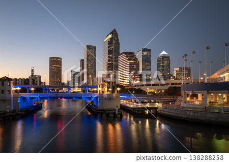 American city skyline of Tampa in Florida. Brightly illuminated commercial buildings and highway bridge over Hillsborough river. Night urban landscape of downtown district in USA. 138288258