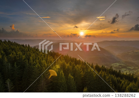 Amazing sunset scenery in wild mountain forest. Dark pine woods illuminated with bright setting sun. Beautiful nature landscape 138288262