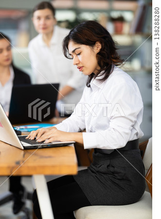 Young woman works on laptop with female colleagues Young woman works on laptop with female colleagues 138288280