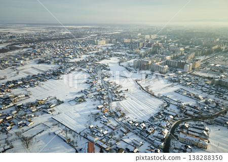 Aerial view of private homes with snow covered roofs in rural suburbs town area in cold winter Aerial view of private homes with snow covered roofs in rural suburbs town area in cold winter 138288350