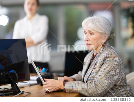 Mature woman working on computer in modern office Mature woman working on computer in modern office 138288355