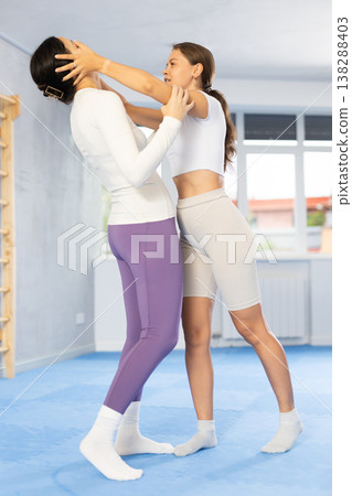 Woman and trainer train painful hold on self-defense course in boxing gym Woman and trainer train painful hold on self-defense course in boxing gym 138288403
