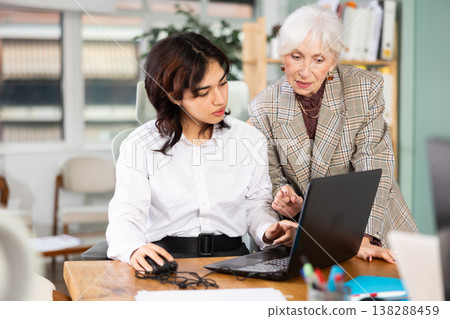 Elderly woman helping young woman with laptop Elderly woman helping young woman with laptop 138288459