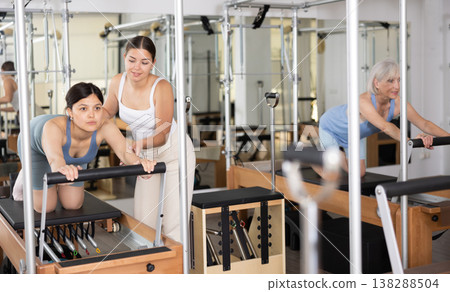 Young asian woman doing exercises on reformer with pilates instructor Young asian woman doing exercises on reformer with pilates instructor 138288504