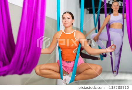 Young woman performing antigravity yoga exercise in gym Young woman performing antigravity yoga exercise in gym 138288510