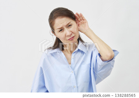 Elderly woman holding her hand over her ear on a white background 138288565