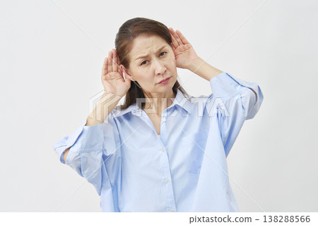 Elderly woman holding her hand over her ear on a white background 138288566