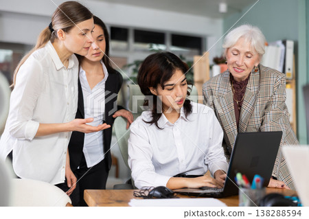 Group of women discussing work around laptop in office 138288594