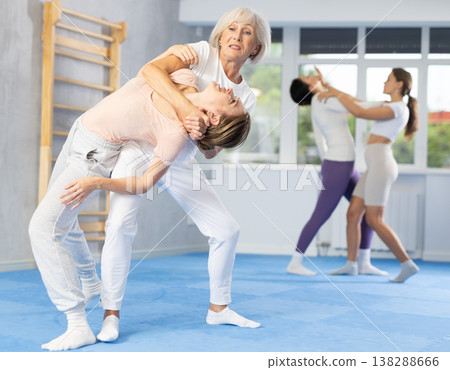 Woman and girl in gym perform basic elements of krav maga self-defense system. 138288666