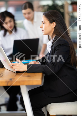 Young woman working on laptop during busy corporate session 138288679