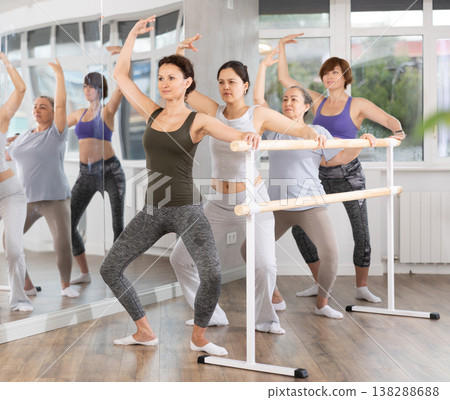 Woman performing demi plie in group barre session in fitness studio 138288688