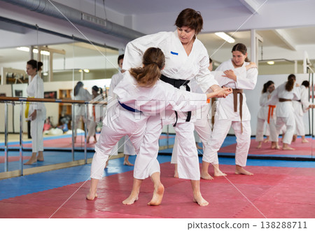 Womens practicing new karate moves in pairs in class with trainer 138288711