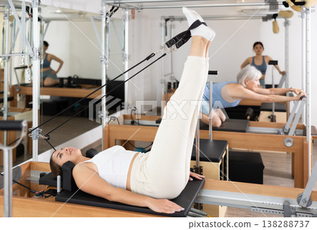 Young girl performing set of pilates exercises on reformer Young girl performing set of pilates exercises on reformer 138288737