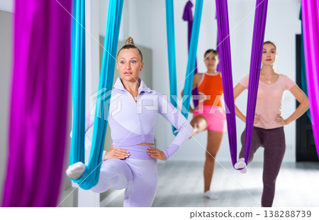Group of beautiful yoga women doing aerial yoga practice in hammocks in fitness club Group of beautiful yoga women doing aerial yoga practice in hammocks in fitness club 138288739