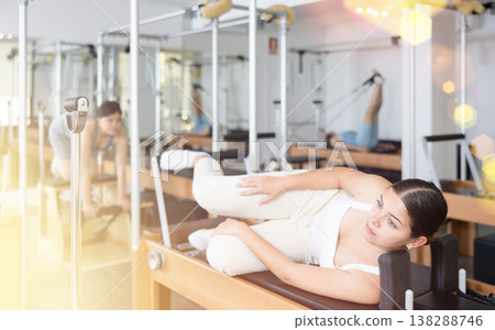 Positive female concentrating on stretching exercise on Pilates equipment bed in studio. Active and healthy lifestyle concept 138288746