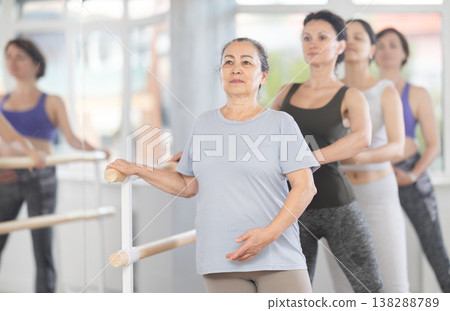 Senior woman practicing battement tendu in beginner ballet class 138288789