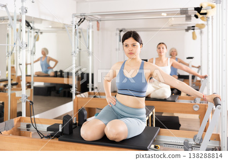 Young positive woman doing Pilates on special equipment in gym Young positive woman doing Pilates on special equipment in gym 138288814