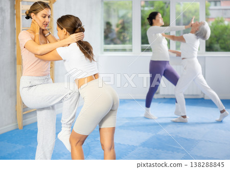 Girl paired up with woman to perform effective impact on pain points while learning self-defense. 138288845